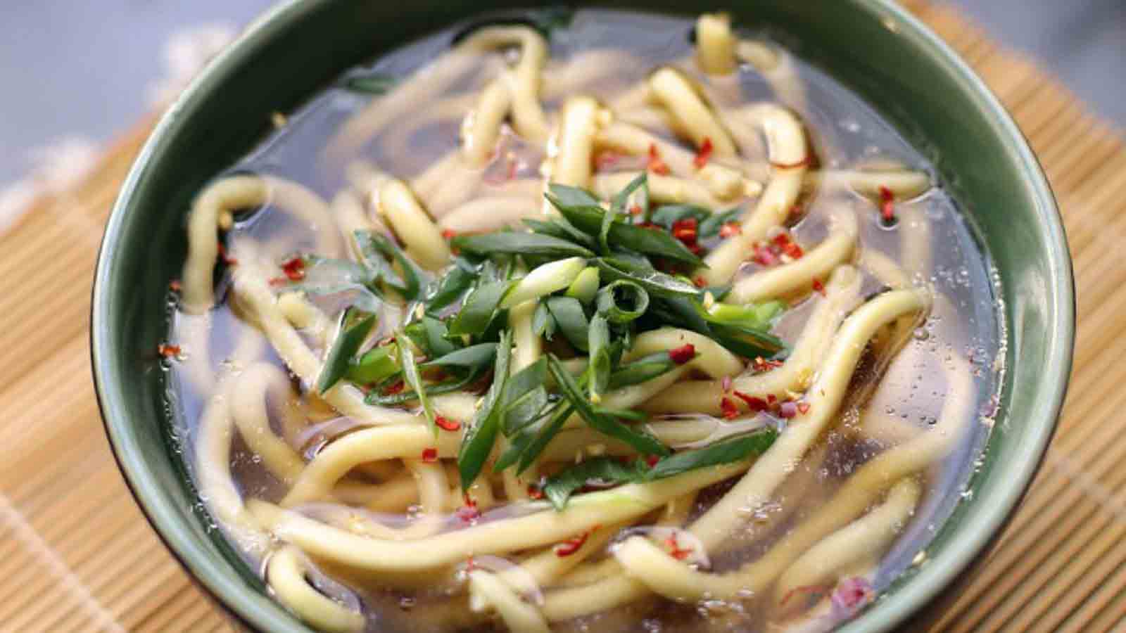 Udon is often served hot as a noodle soup in its simplest form, as kake udon, in a mildly flavoured broth called kakejiru, which is made of dashi, soy sauce, and mirin. It is usually topped with thinly chopped scallions. Other common toppings include tempura, often prawn or kakiage (a type of mixed tempura fritter), or aburaage, a type of deep-fried tofu pockets seasoned with sugar, mirin, and soy sauce. A thin slice of kamaboko, a halfmoon-shaped fish cake, is often added. Shichimi can be added to taste.Source: https://en.wikipedia.org/wiki/Udon
